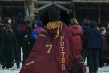 Harry Potter corre hacia el campo de Quidditch con túnica y escoba en mano, listo para su primer partido en Hogwarts.